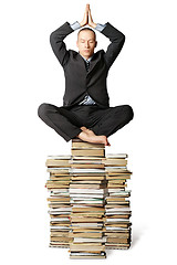 Image showing businessman in lotus pose with many books near