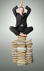 Image showing businessman in lotus pose with many books near