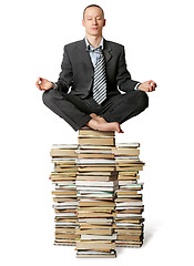Image showing businessman in lotus pose with many books near
