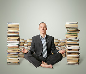 Image showing businessman in lotus pose with many books near