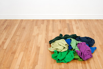 Image showing Pile of colorful clothes on the wooden floor