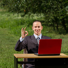 Image showing man with red laptop working outdoors