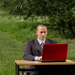 Image showing man with red laptop working outdoors