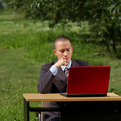 Image showing man with red laptop working outdoors