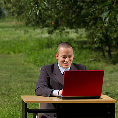 Image showing man with red laptop working outdoors