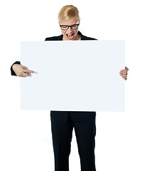 Image showing Successful business female pointing at white blank billboard