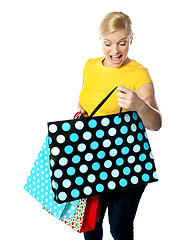 Image showing Young girl looking excitedly inside her shopping bag