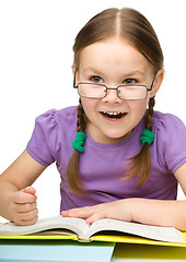 Image showing Cute little girl hits a book with fist