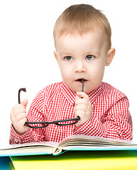 Image showing Little child play with book and glasses