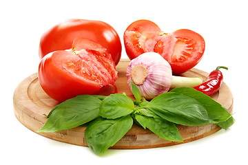 Image showing Ripe tomatoes, garlic and basil on a wooden board. 