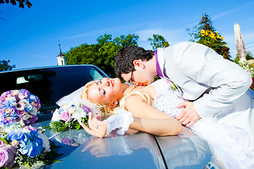 Image showing groom and bride kissing on a car cowl