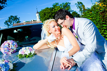 Image showing groom and bride kissing on a car cowl