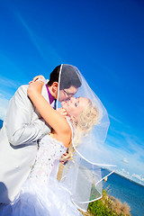 Image showing tender kiss of happy groom and bride on a sea coast