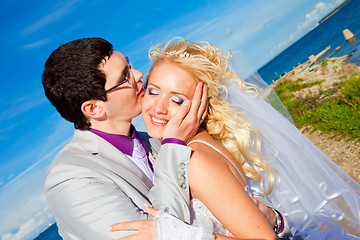 Image showing tender kiss of happy groom and bride on a sea coast