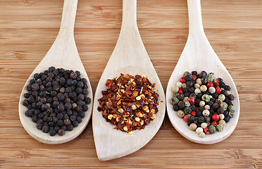 Image showing Three types of pepper on wooden spoons