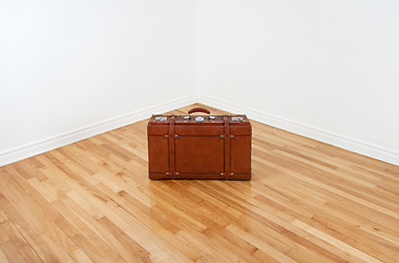 Image showing Vintage leather suitcase in empty room corner