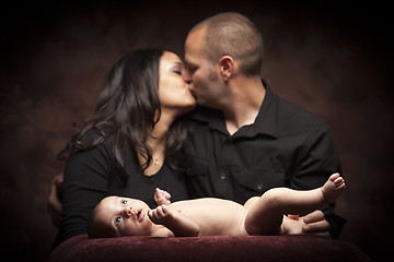 Image showing Mixed Race Couple Kiss While Baby Lays on Pillow
