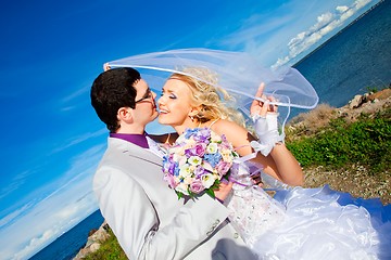 Image showing tender kiss of happy groom and bride on a sea coast