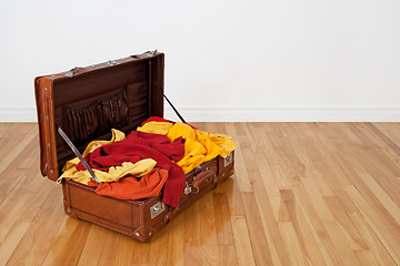 Image showing Leather suitcase full of orange and yellow clothing