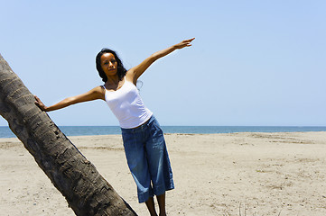 Image showing Woman leaning on a palm tree