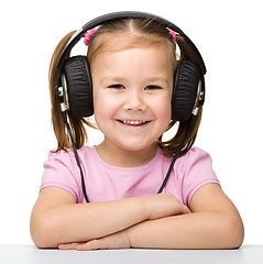 Image showing Cute little girl enjoying music using headphones