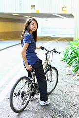 Image showing young woman riding bicycle in city