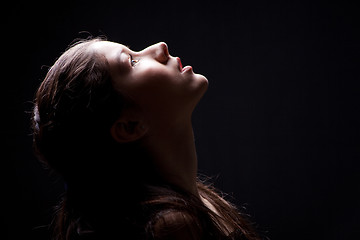 Image showing young girl lasting up to light on black