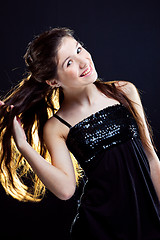 Image showing teenager girl showing  beautiful healthy long dark hair  on black