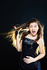 Image showing teenager girl showing  beautiful healthy long dark hair  on black