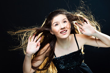 Image showing  cute girl  lasting towards to wind and light on black