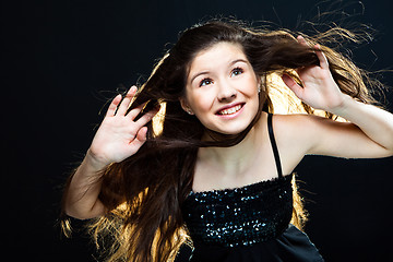 Image showing  cute girl  lasting towards to wind and light on black