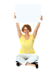 Image showing Seated woman holding blank billboard