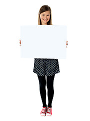 Image showing Attractive smiling cute girl holding blank poster