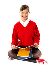 Image showing Pretty school girl seated on floor, holding book