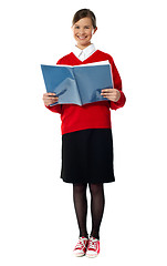 Image showing Smiling girl standing with exercise book