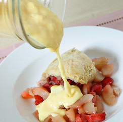 Image showing Pouring custard on fruit pudding