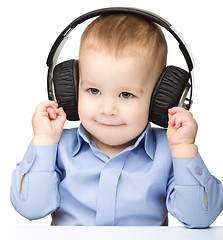 Image showing Cute little boy enjoying music using headphones