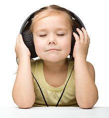 Image showing Cute little girl enjoying music using headphones