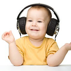 Image showing Cute little boy enjoying music using headphones