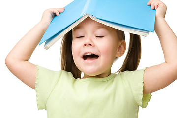 Image showing Cute little girl plays with book