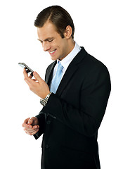 Image showing Male executive smiling as he reads message on his mobile