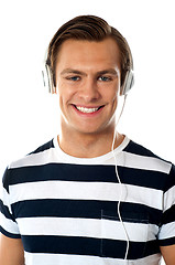 Image showing Smiling young man listening to music through headphones