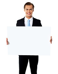 Image showing Young businessman holding white blank billboard