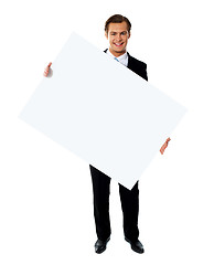 Image showing Young corporate male holding tilted blank billboard