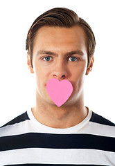 Image showing Good looking guy with heart shaped paper on his mouth