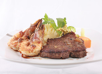 Image showing A steak and shrimp dinner over a plaid tablecloth 