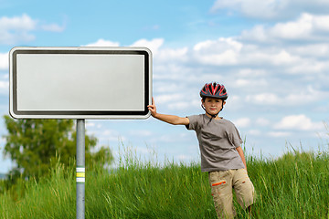 Image showing Boy cyclist leaning on blank sign