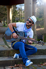 Image showing young man is playing a guitar and singing