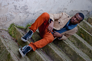 Image showing black man sitting on stairs outdoor with jacket and scarf