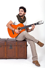 Image showing young man is playing a guitar and singing